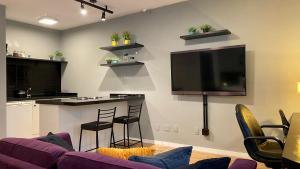 uma sala de estar com um bar e uma televisão na parede em QSA - Anora Spaces - Metropolis Alphaville em Barueri