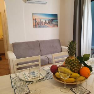 una mesa con un bol de frutas y copas de vino en Insardinia House trilocale a 200mt dalla spiaggia en Olbia