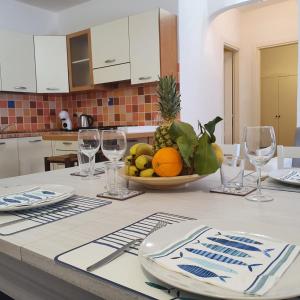 - une table avec un bol de fruits et des verres à vin dans l'établissement Insardinia House trilocale a 200mt dalla spiaggia, à Olbia