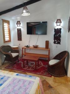 ein Wohnzimmer mit einem TV, einem Tisch und Stühlen in der Unterkunft Pousada Yuste Beach Farm in Paracuru