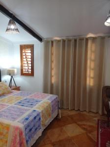 1 dormitorio con 1 cama y una ventana con cortinas en Pousada Yuste Beach Farm, en Paracuru