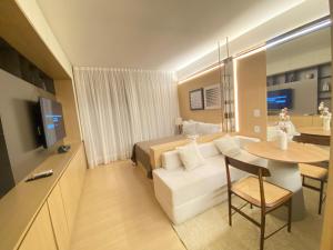 a room with a bed and a white couch and a table at Luxuoso Studio Setor Marista - 454 in Goiânia