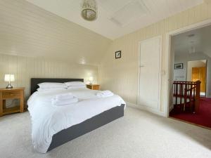 a bedroom with a large bed with white sheets at Rhianchaitel House in Bettyhill