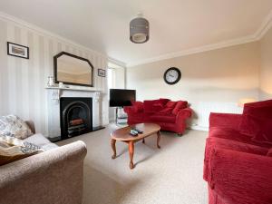 a living room with a red couch and a table at Rhianchaitel House in Bettyhill