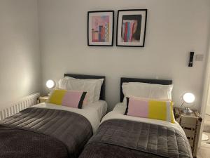 two beds sitting next to each other in a bedroom at Hill Garth Cottage - Luxury hotel style 2 bed with hot tub in Wooler