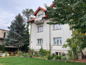 a large white building with a balcony in a yard at Glada in Jastarnia