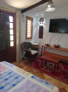 a living room with a table and a chair and a television at Pousada Yuste Beach Farm in Paracuru