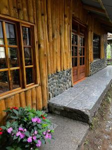 un edificio de madera con una puerta y algunas flores en CABAÑA EL CEDRO, en San Vito