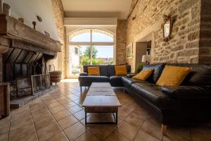 a living room with a leather couch and a fireplace at La Maison de Beaume in Créancey