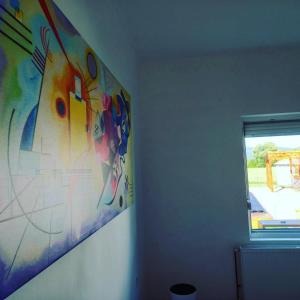 una camera con un dipinto sul muro e una finestra di Skriveni raj a Gornji Milanovac