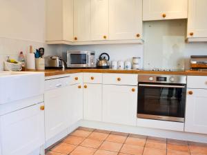 a white kitchen with white cabinets and a microwave at Cranberry Cottage in South Creake