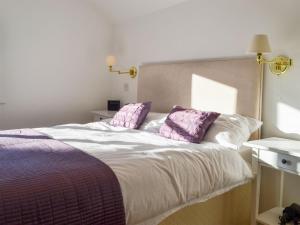 a bedroom with a bed with purple and white pillows at Cranberry Cottage in South Creake