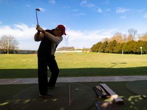 un hombre balanceando un club de golf en un campo de golf en Mercure Parc du Coudray - Barbizon, en Le Coudray-Montceaux