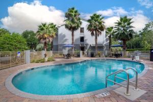 a swimming pool with palm trees in front of a house at Best Western Plus Tallahassee North Hotel in Tallahassee