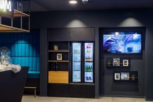 a room with a refrigerator and a tv on a wall at elaya hotel goeppingen in Göppingen