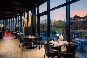 a dining room with tables and chairs and windows at elaya hotel kevelaer in Kevelaer