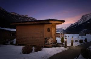 a small building in the snow with mountains in the background at KUHOTEL by Rilano in Waidring
