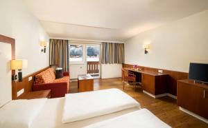 ヴァイトリングにあるKUHOTEL by Rilanoのベッドとデスクが備わるホテルルームです。