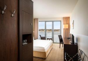 a hotel room with a bed and a desk and a window at The Rilano Hotel Hamburg in Hamburg