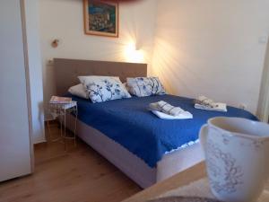 1 dormitorio con 1 cama azul y 2 toallas en Old marine house en Tivat