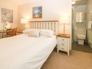 a bedroom with a white bed and a bathroom at Riverside House in Amlwch