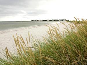 una playa con césped y el océano y un muelle en 6 person holiday home in Hadsund, en Hadsund