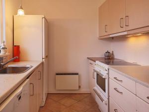 cocina con armarios blancos, fregadero y nevera en 4 person holiday home in Dronningm lle, en Dronningmølle