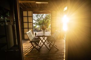 einen Tisch und Stühle auf einer Veranda mit Sonnenschein in der Unterkunft Fare Vavi in Matiti
