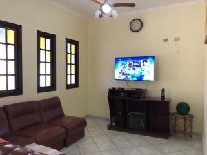 uma sala de estar com um sofá e uma televisão de ecrã plano em Sobrado 4 dorm Cond. Fechado Praia da Mococa Caraguatatuba em Caraguatatuba