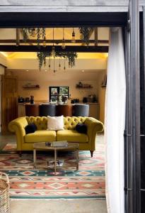 uma sala de estar com um sofá amarelo e uma mesa em Luxury Barn with Hot Tub, Spa Treatments, Private Dining em Little Budworth