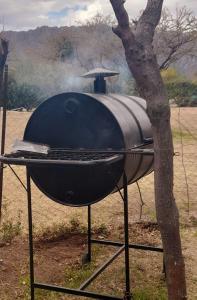 a barbecue grill sitting next to a tree at Cabaña Balcón Serrano in Cortaderas