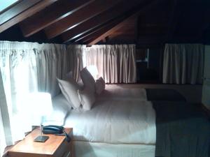 a bedroom with a white bed with a wooden ceiling at Hotel Villadesella in Ribadesella