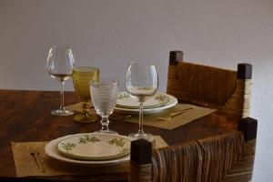 einem Holztisch mit Weingläsern und Tellern darauf in der Unterkunft Casa de Diana in Évora