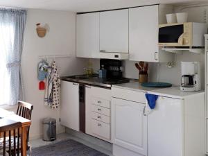 a white kitchen with white cabinets and a microwave at 2 person holiday home in Falkenberg in Falkenberg