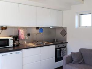 cocina con armarios blancos, fregadero y microondas en Holiday home VARBERG X en Varberg