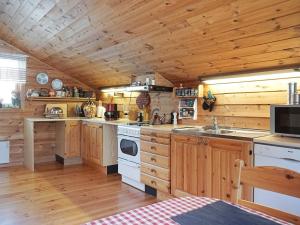 La cuisine est équipée de placards en bois et d'un four avec plaques de cuisson. dans l'établissement 6 person holiday home in STR MSTAD, à Strömstad