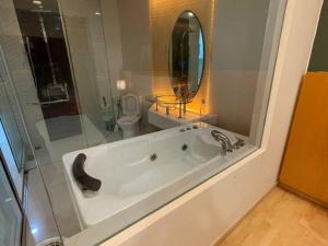 a bathroom with a tub and a toilet and a mirror at Stylish Romantic Couples Getaway at KL City 1419 in Kuala Lumpur +3 photos