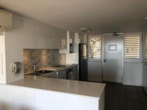 a white kitchen with a sink and a refrigerator at Fremantle Harbour Townhouse in Fremantle