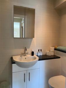 a bathroom with a sink and a toilet and a mirror at Cosy 3 bedroom apartment in central Portrush with sea views in Portrush