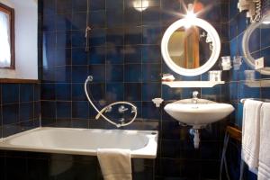 a bathroom with a sink, mirror, and bathtub at Hotel Dolonne in Courmayeur