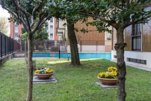deux grands bols de fleurs assis entre deux arbres dans l'établissement Milano City Apartments - Parking and Comfort - Spacious Apt up to 8 Pax, à Milan