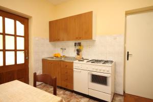 a kitchen with a white stove and wooden cabinets at Family friendly seaside apartments Ugljan - 828 in Ugljan