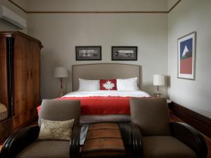 BloomfieldにあるThe Eddie Hotel and Farmのベッドルーム1室(赤い毛布と椅子2脚付)