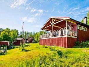a red building with a deck on a grass field at 7 person holiday home in JARFJORD in Karpbukt