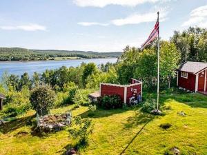 a house with an american flag next to a lake at 7 person holiday home in JARFJORD in Karpbukt