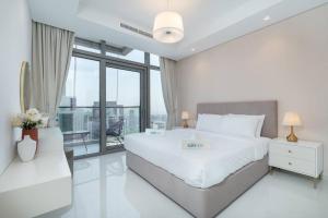 a white bedroom with a large bed and a large window at Opulent Hollywood Styled Flat in Paramount Tower in Dubai