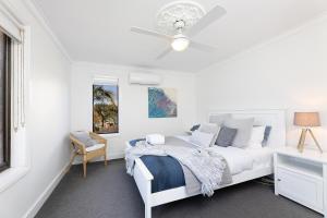 a white bedroom with a bed and a ceiling fan at Sand Dunes in Forster