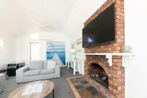 a living room with a fireplace with a flat screen tv at Sand Dunes in Forster