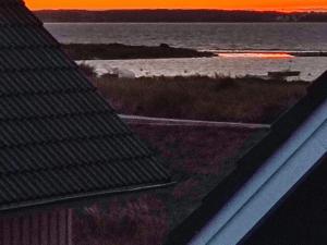 einen Blick auf das Meer bei Sonnenuntergang von einem Dach in der Unterkunft 4 person holiday home in Wendtorf in Wendtorf