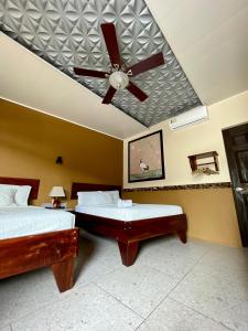a bedroom with two beds and a ceiling fan at Hotel Wilson Condega in Liberia